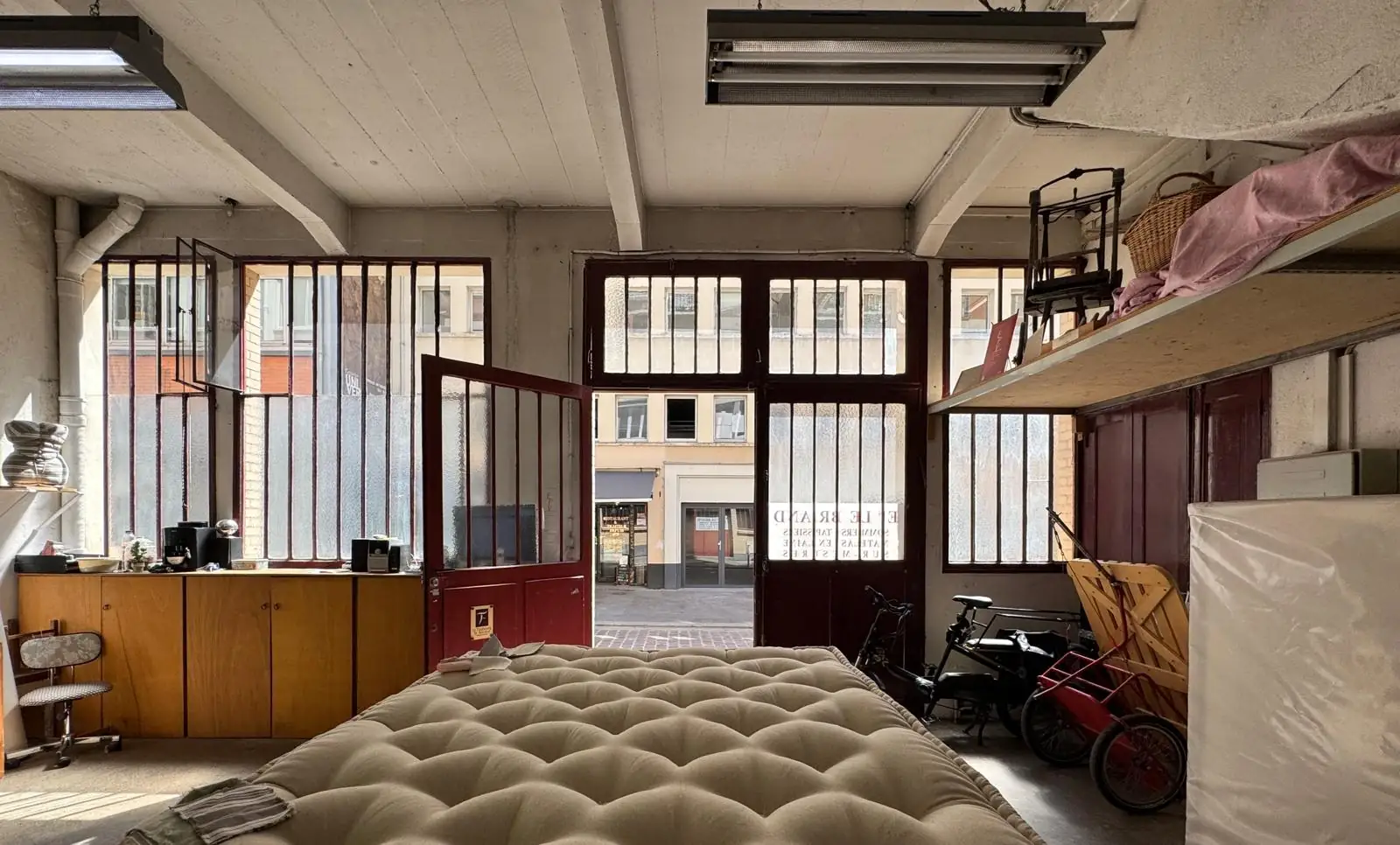 L’atelier Le Briand à Paris : un matelas en laine capitonné devant la porte vitrée ouverte sur la rue