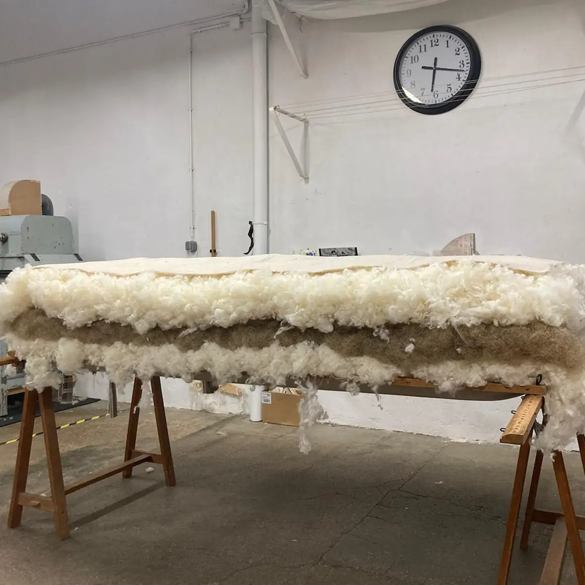 Wool and animal-hair mattress open on trestles in the workshop, before the ticking is closed over the sheep’s wool and animal-hair core