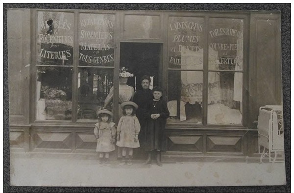 Old photograph of a Parisian bedding shop, a family posing on the doorstep